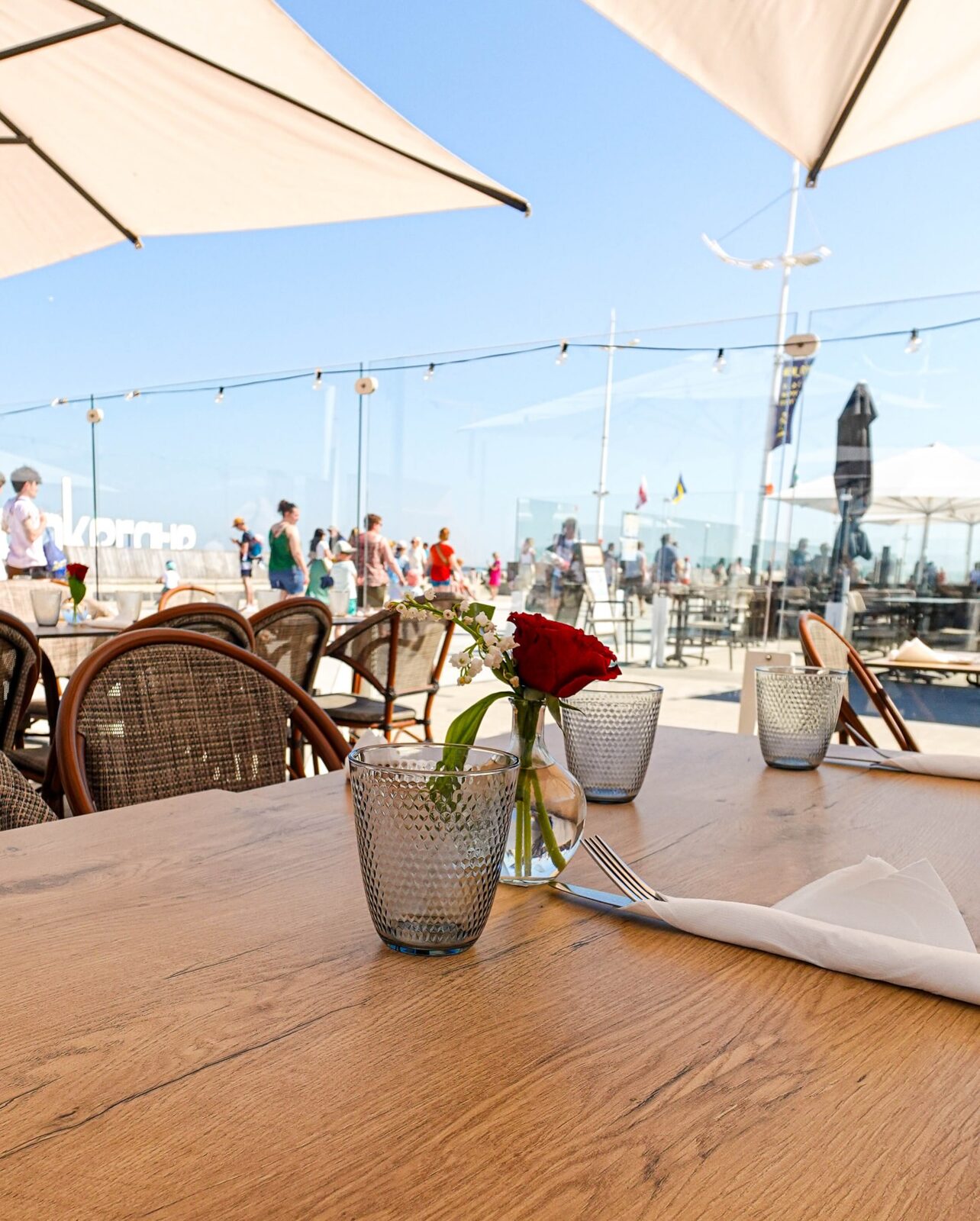 Table en terrasse avec rose et muguet, vue sur la plage de Dunkerque